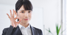 笑顔でOKポーズをとる女性の写真